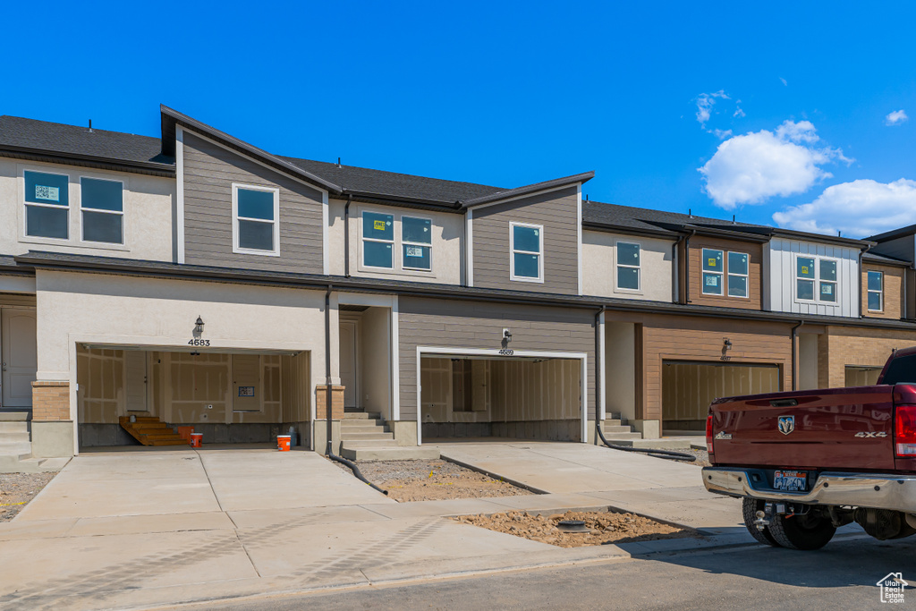 View of property featuring a garage, driveway, and entry steps