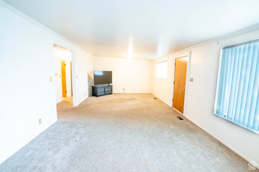 Unfurnished living room featuring carpet floors and ornamental molding