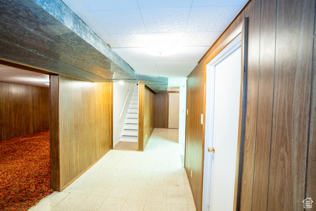 Hallway with wooden walls, light flooring, and stairs