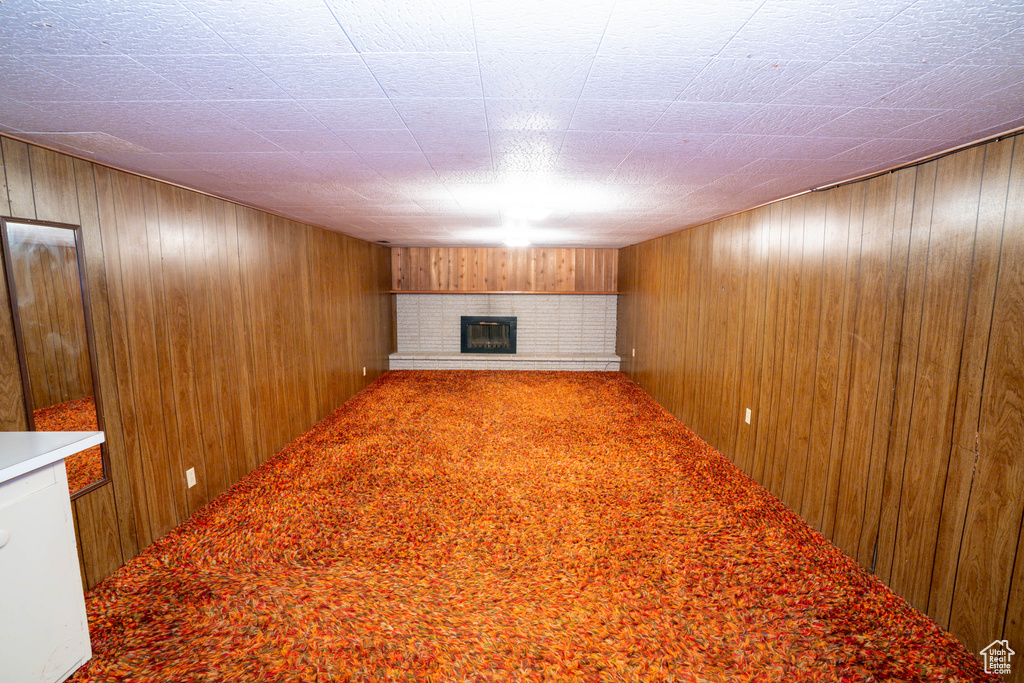 Unfurnished living room featuring a fireplace and wood walls