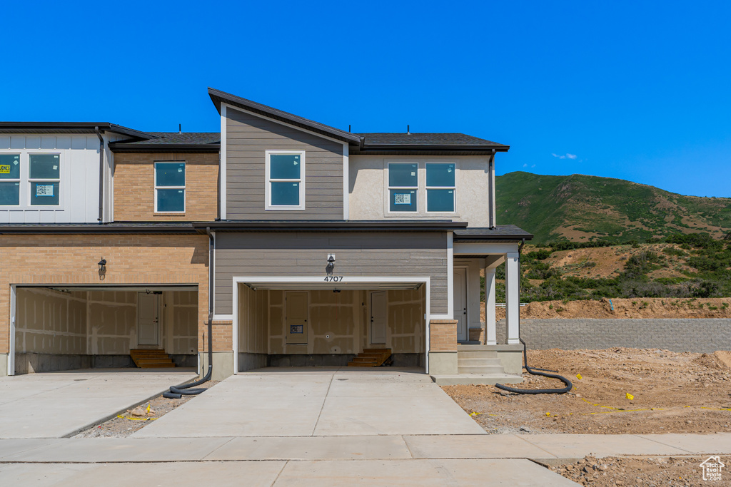 View of front of house with concrete driveway, an attached garage, entry steps, and a mountain view