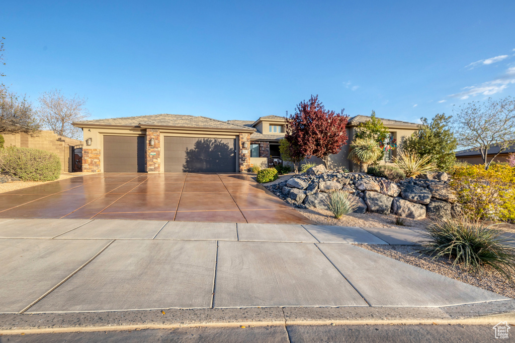 View of front facade featuring concrete driveway, stucco siding, stone siding, and a garage