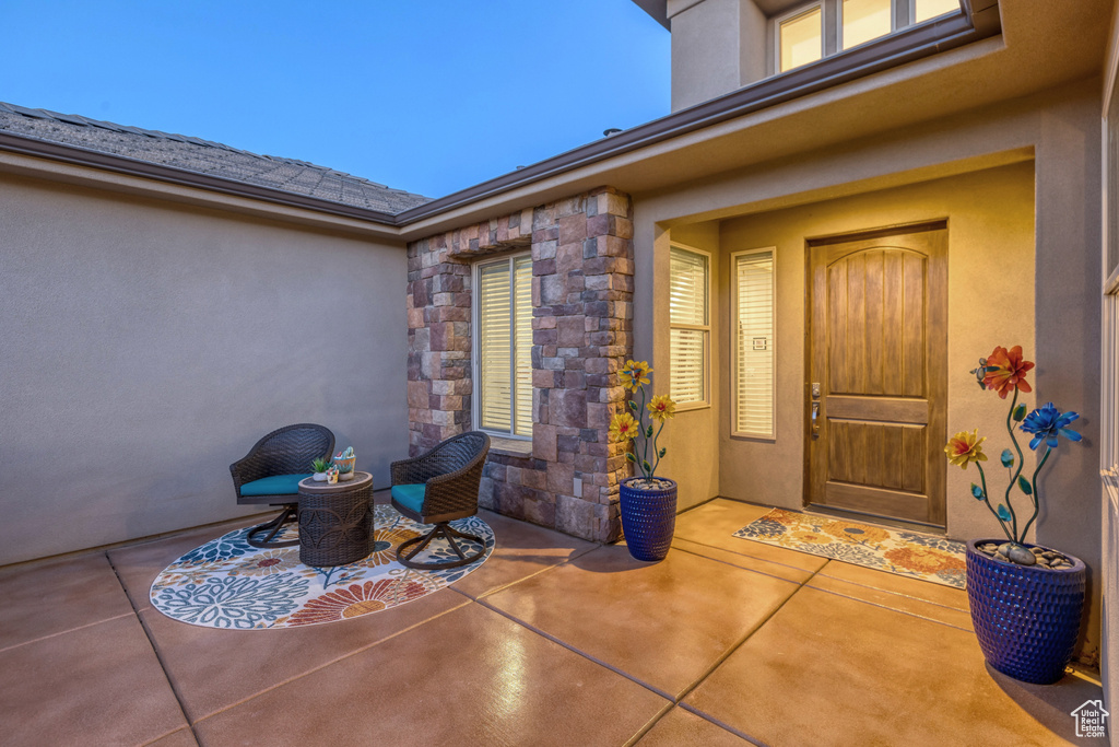 Property entrance with a patio, stucco siding, and stone siding
