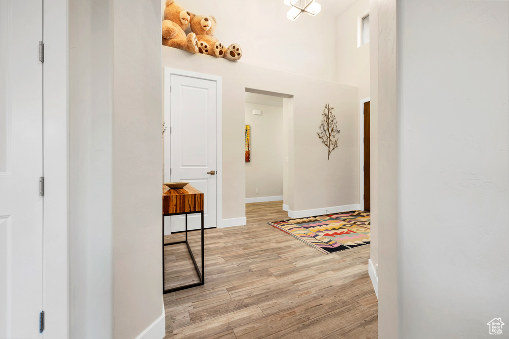Corridor with light wood-style floors, baseboards, and a towering ceiling