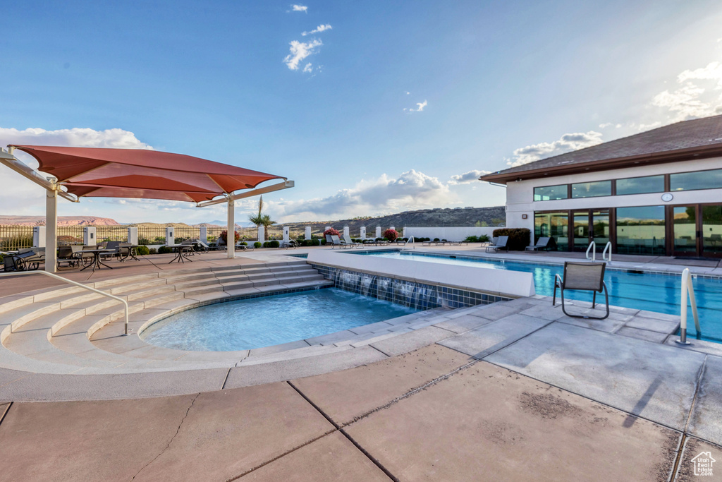 Community pool featuring a patio area and fence