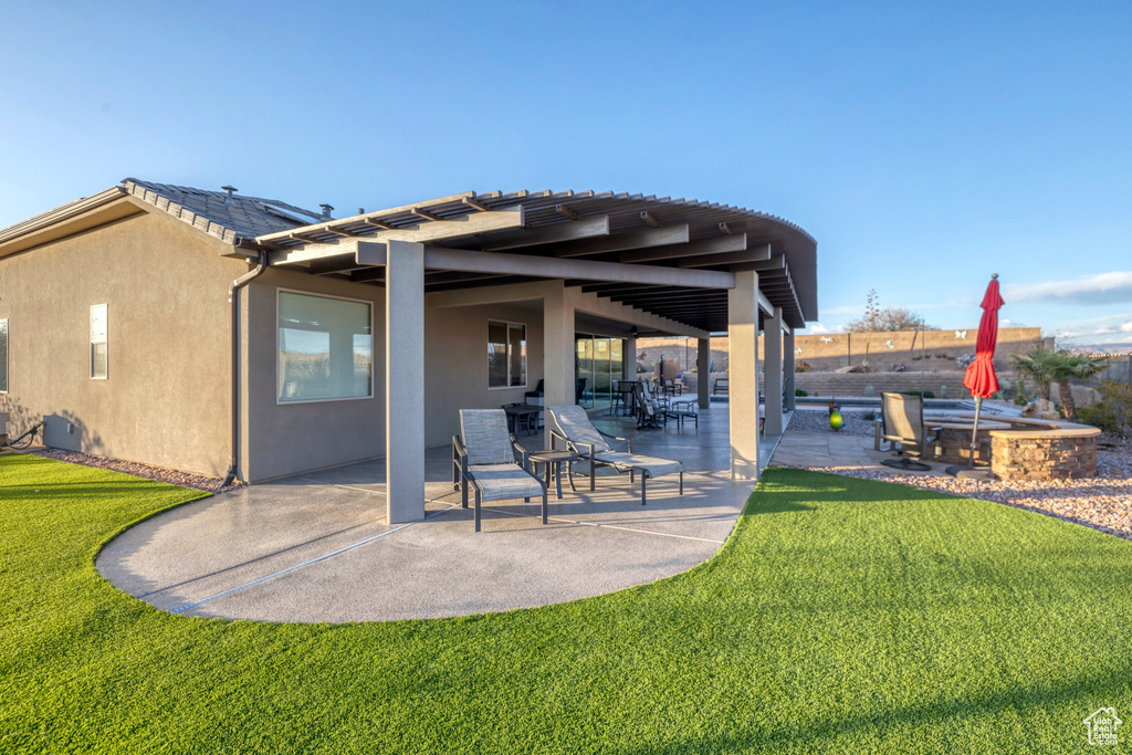 Rear view of house featuring a yard, a patio, and stucco siding