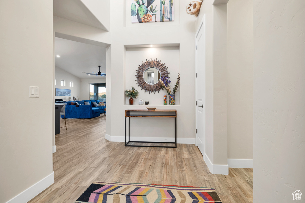 Hall featuring wood finished floors, baseboards, and lofted ceiling