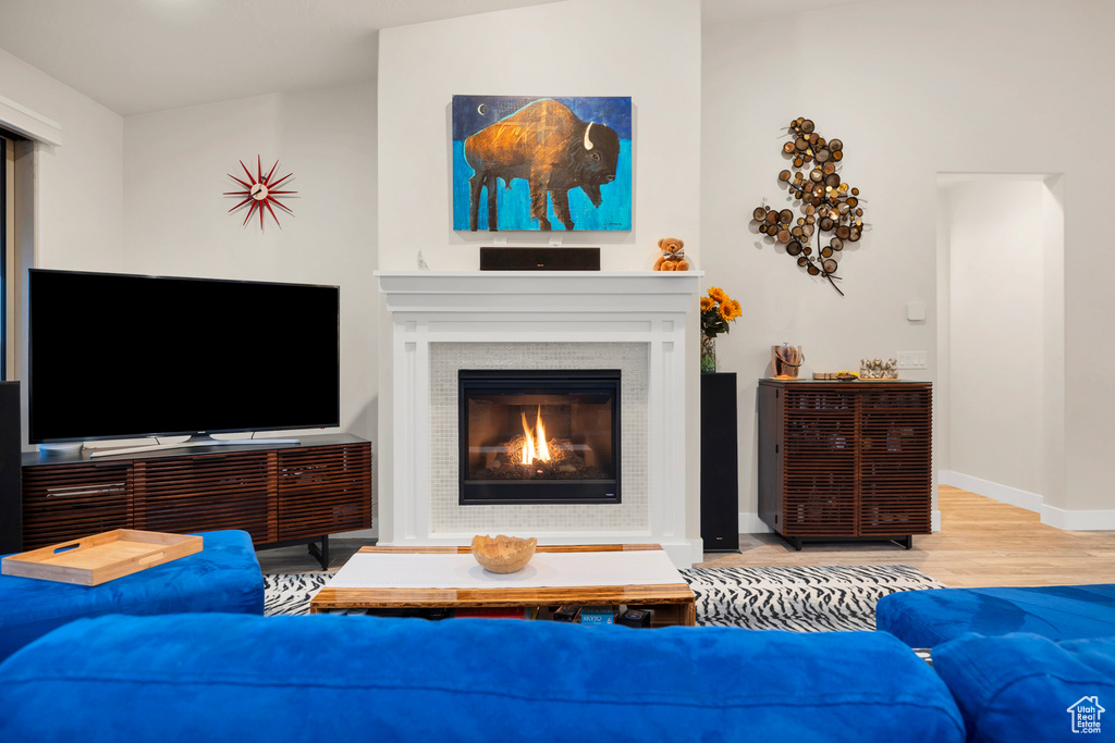 Living area with baseboards, a glass covered fireplace, and wood finished floors