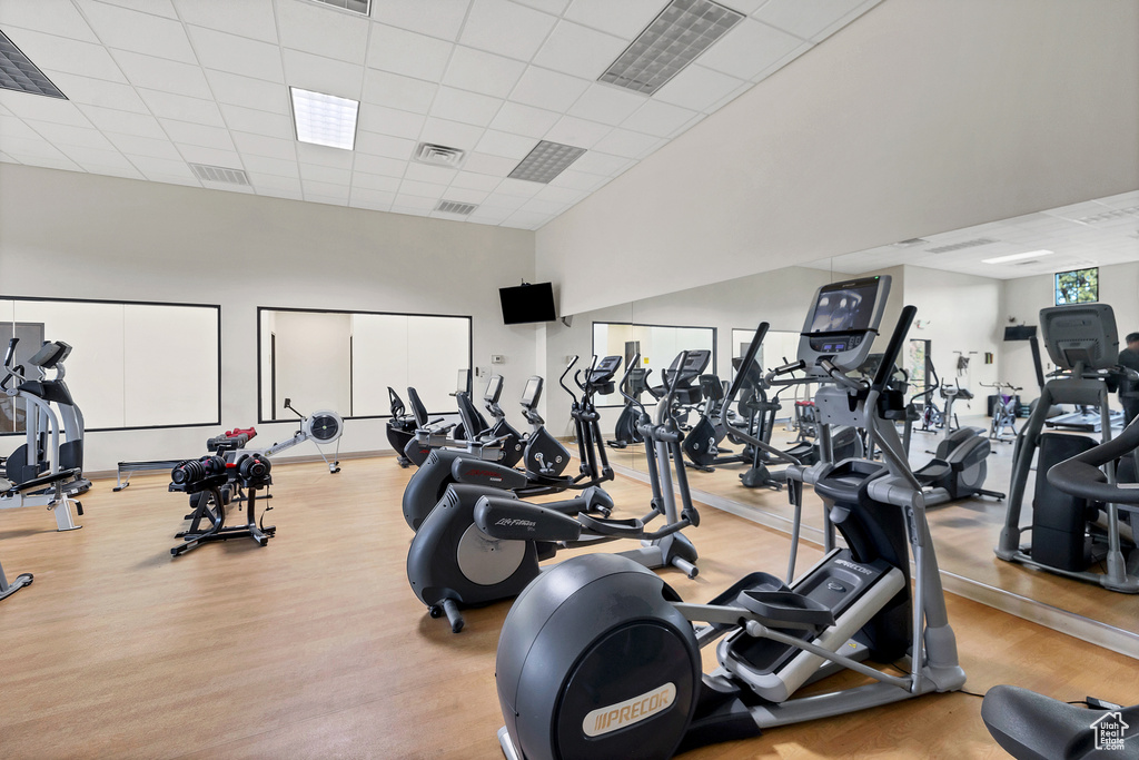 Workout area featuring a towering ceiling, visible vents, a paneled ceiling, and wood finished floors
