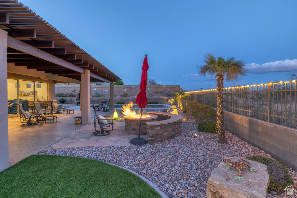 View of patio with a fenced backyard and a fire pit
