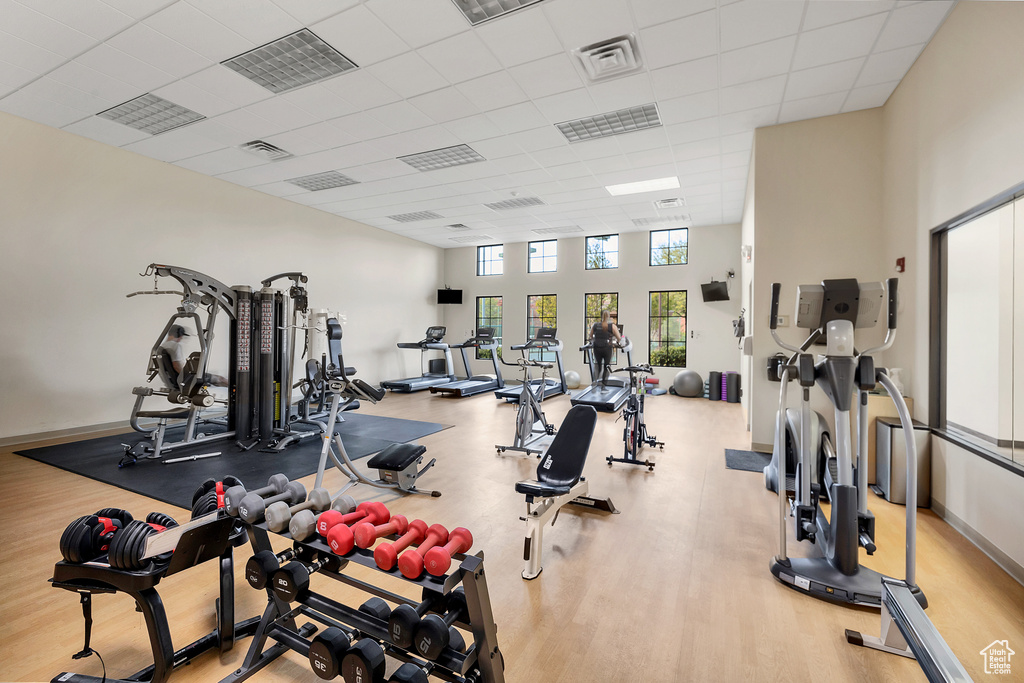 Workout area with a paneled ceiling, a high ceiling, wood finished floors, and visible vents