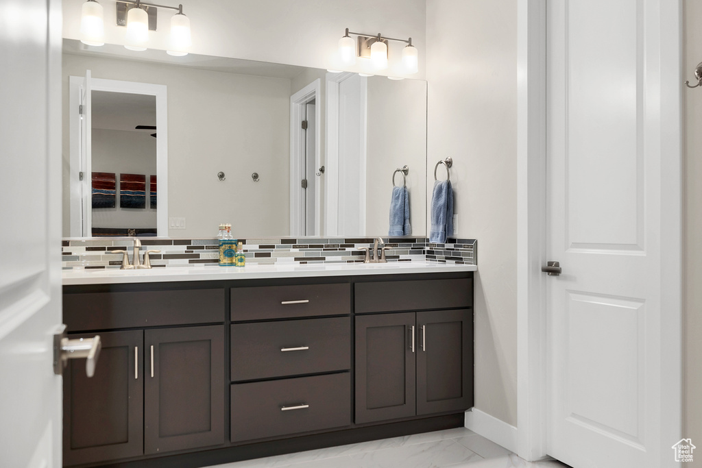 Bathroom with a sink, tasteful backsplash, and marble finish floor