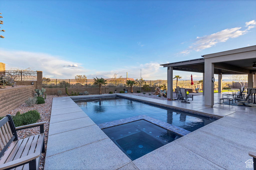 View of pool featuring a patio area, a fenced backyard, and a pool with connected hot tub