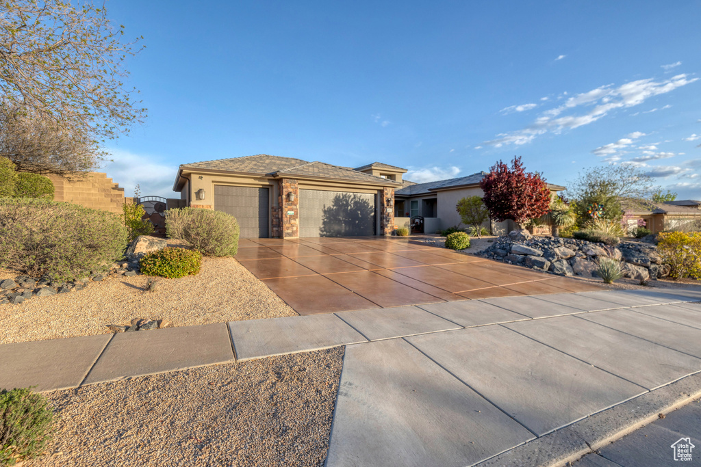 View of front of house with an attached garage, driveway, stucco siding, and a gate