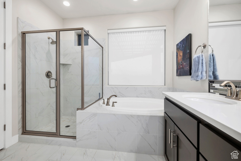 Full bath with a marble finish shower, vanity, and a garden tub