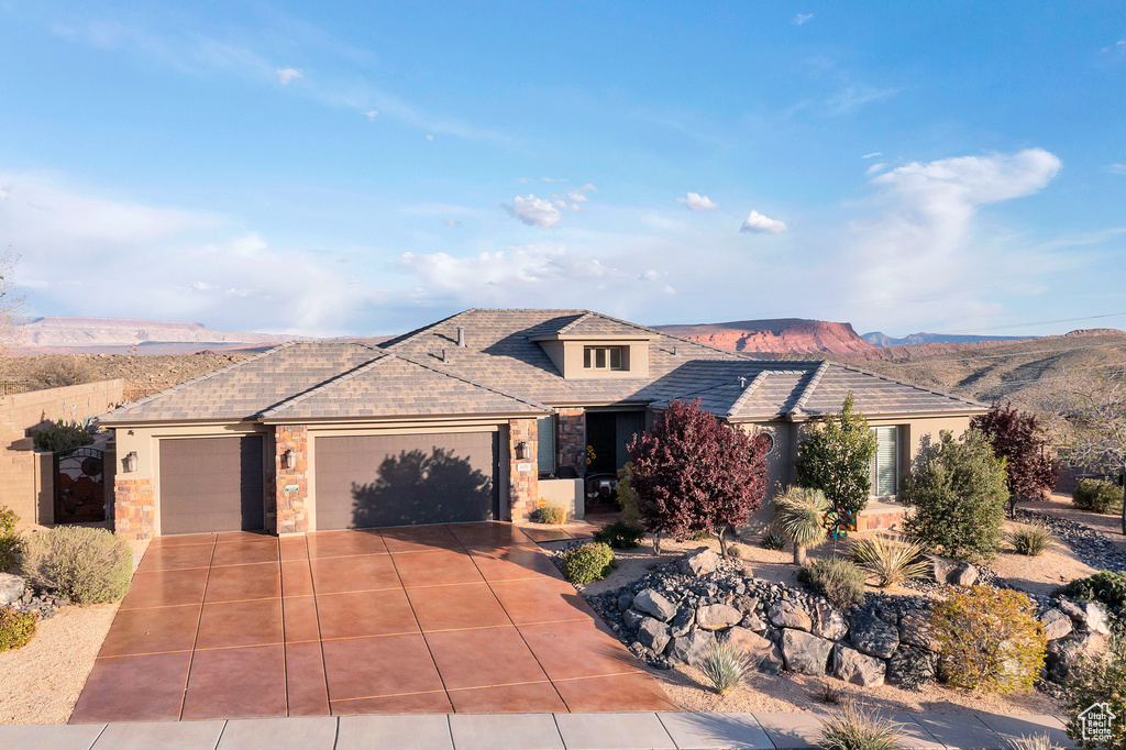 View of front of home with an attached garage, stone siding, driveway, and stucco siding