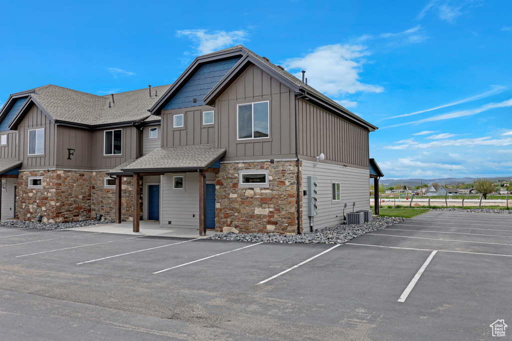 View of building exterior featuring uncovered parking and central AC