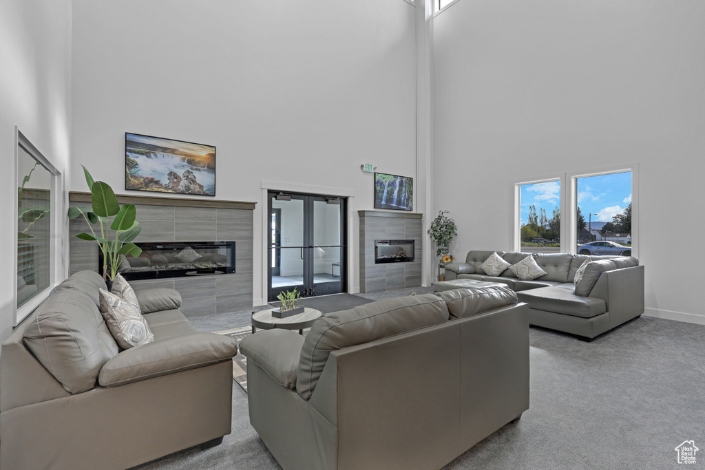 Living room with a tile fireplace, a high ceiling, carpet floors, and baseboards