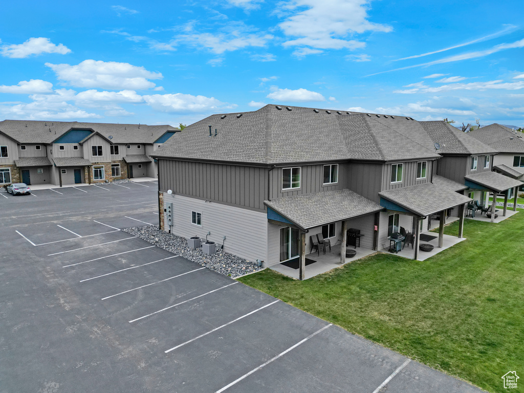 Back of house featuring roof with shingles, uncovered parking, board and batten siding, and a residential view