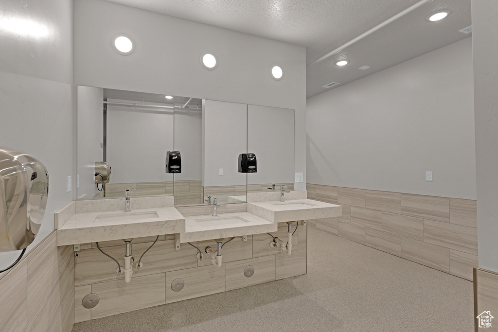 Full bath with tile walls, recessed lighting, vanity, and a wainscoted wall