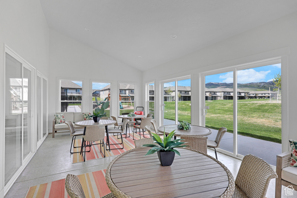 Sunroom / solarium featuring outdoor dining area, high vaulted ceiling, speckled floor, and a residential view