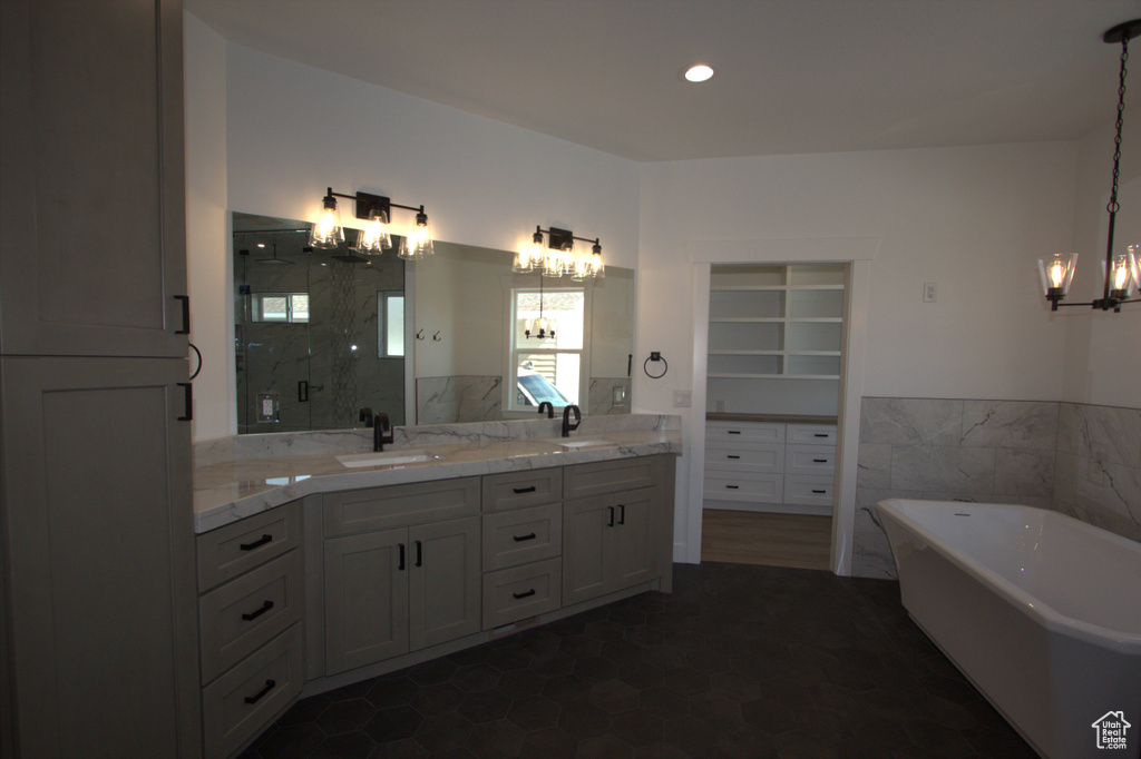 Full bath featuring a sink, a marble finish shower, a freestanding tub, and a chandelier