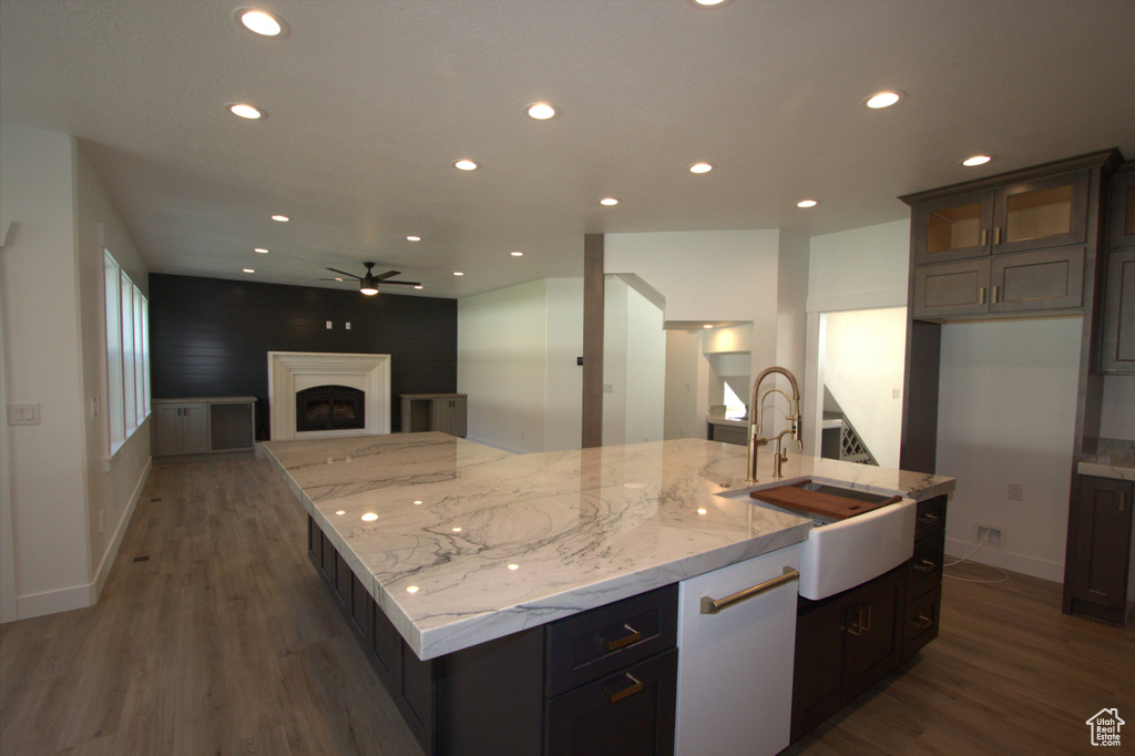 Kitchen featuring ceiling fan, a large island with sink, wood finished floors, a sink, and open floor plan
