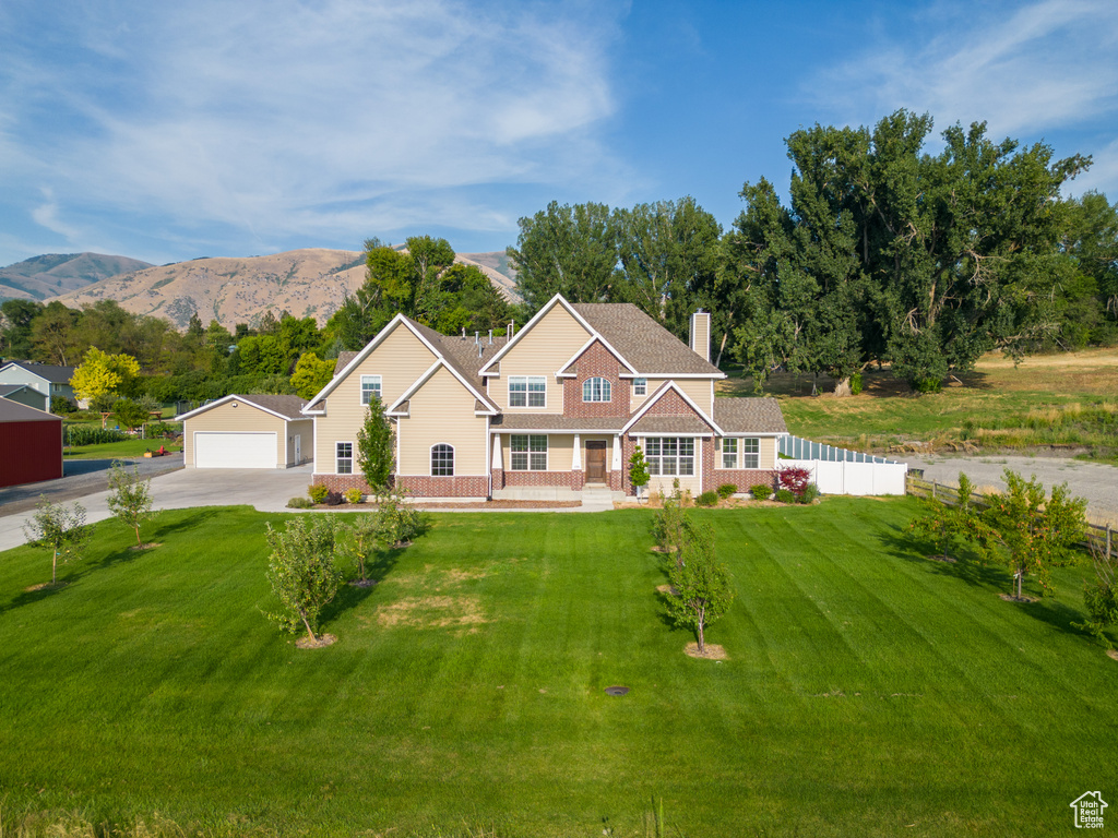 View of front of property featuring a front yard, fence, a garage, a porch, and a mountain view