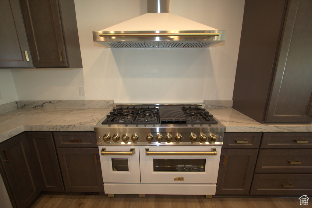 Kitchen featuring exhaust hood, dark wood-style floors, double oven range, and dark brown cabinetry