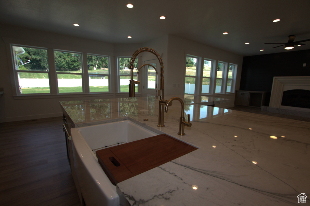 Kitchen with a sink, open floor plan, recessed lighting, and light stone counters