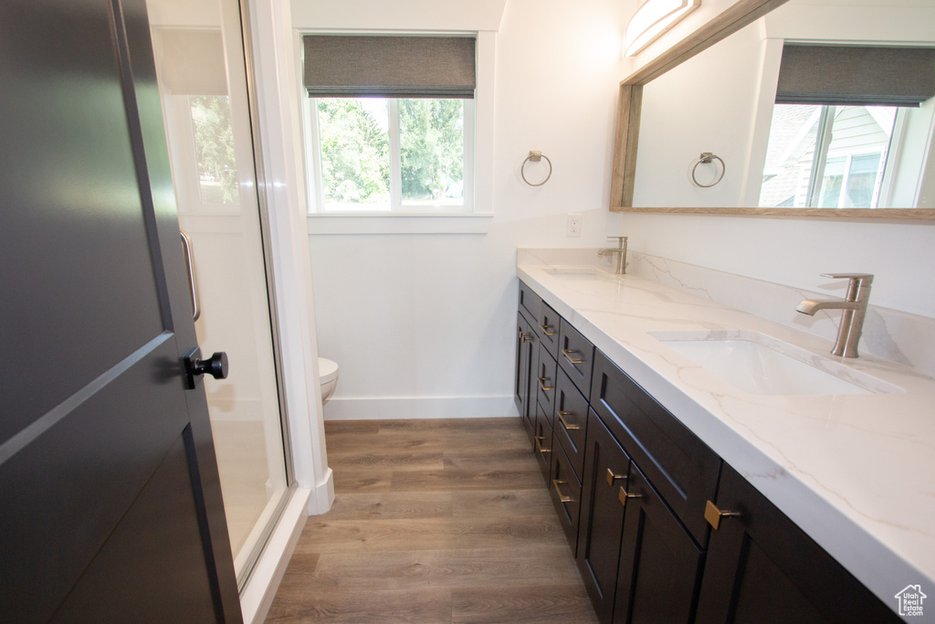 Full bath with toilet, wood finished floors, double vanity, and a sink