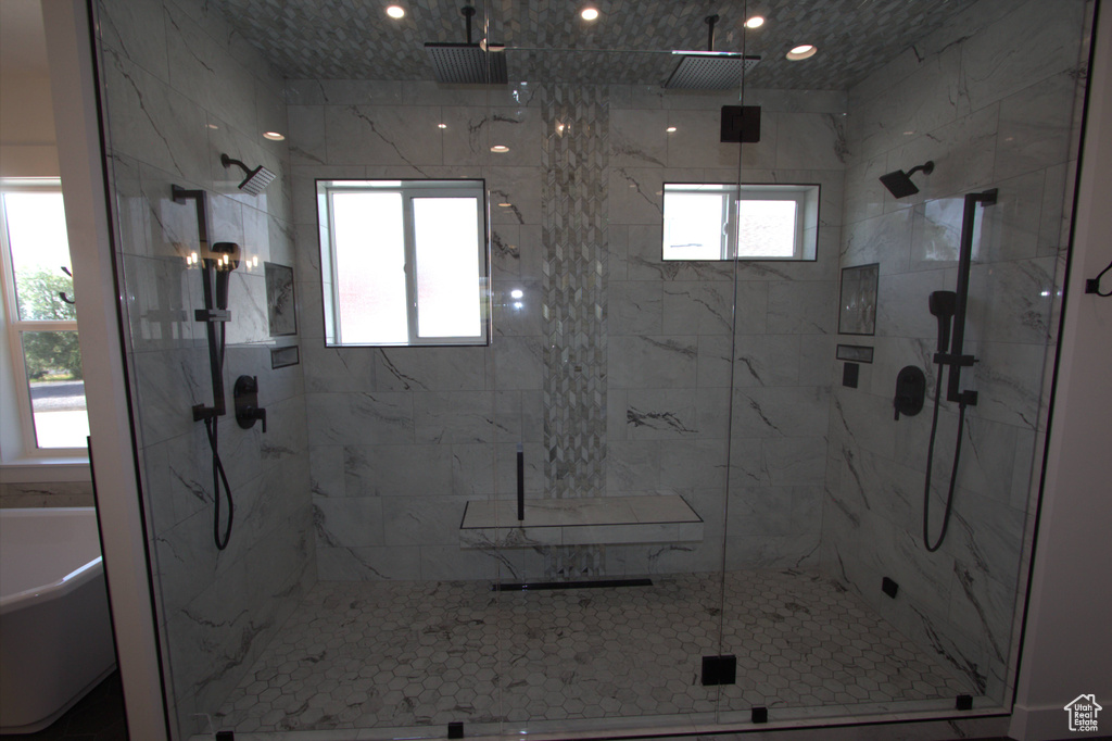 Bathroom with a wealth of natural light, a marble finish shower, and a soaking tub