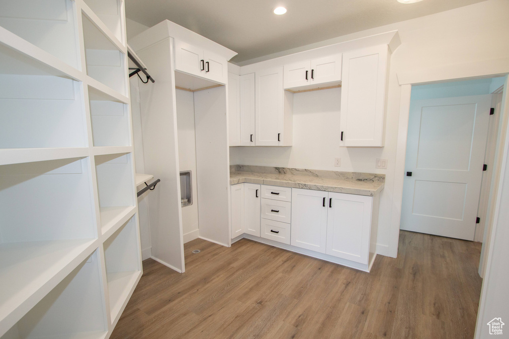 Interior space featuring white cabinets, light wood-type flooring, light countertops, and open shelves