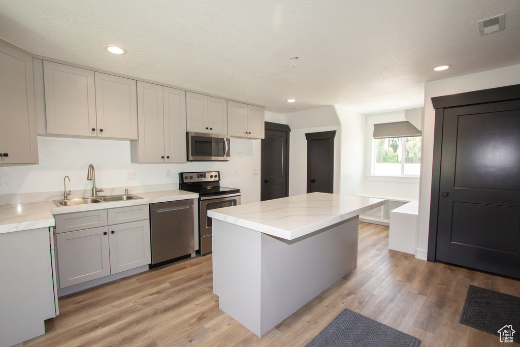 Kitchen with a sink, light wood-type flooring, appliances with stainless steel finishes, recessed lighting, and a kitchen island
