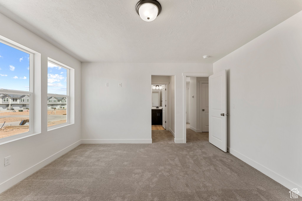 Carpeted empty room with baseboards and a textured ceiling