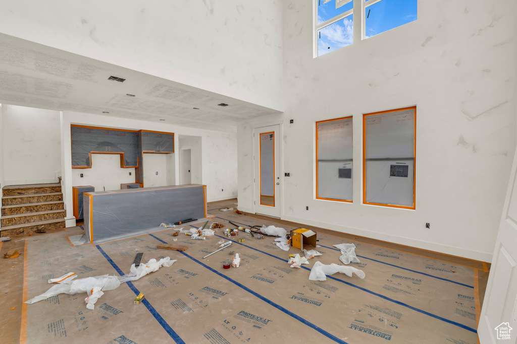 Unfurnished living room with stairs, a towering ceiling, and baseboards