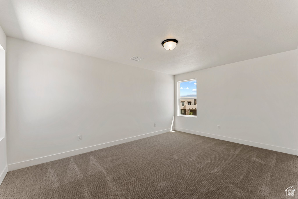 Spare room with dark carpet and baseboards