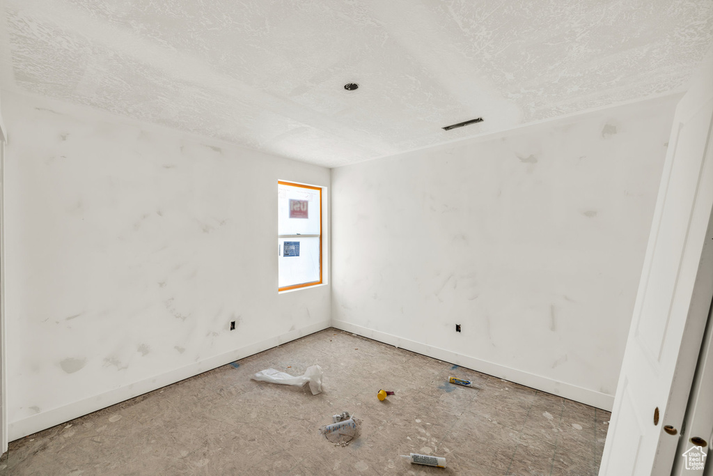 Unfurnished room featuring visible vents, a textured ceiling, and baseboards