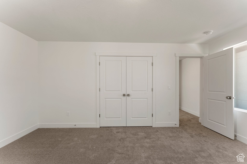 Unfurnished bedroom with light colored carpet and a closet