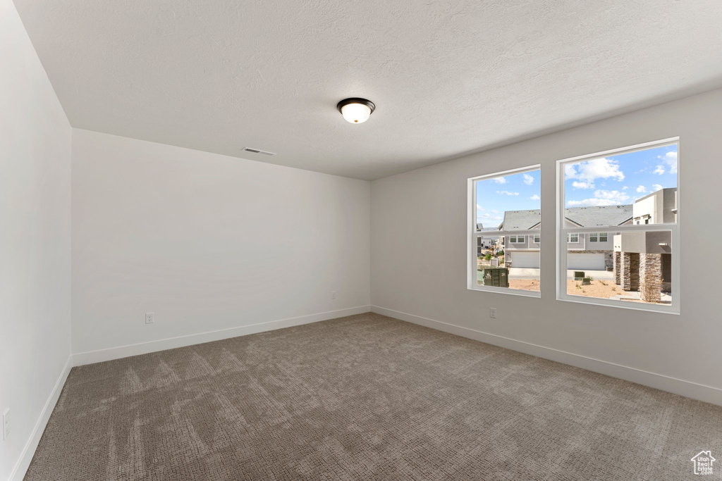 Carpeted spare room with baseboards and a textured ceiling