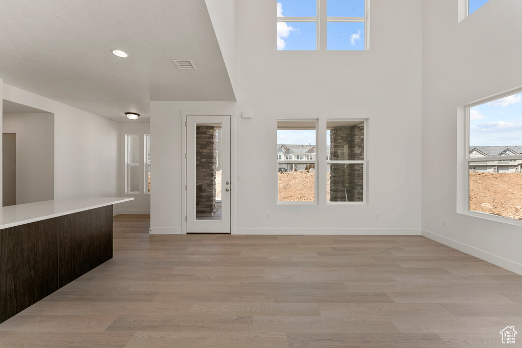 Foyer entrance with healthy amount of natural light, light wood-type flooring, a towering ceiling, and recessed lighting