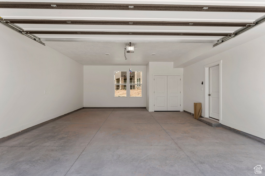 Garage featuring a garage door opener and baseboards