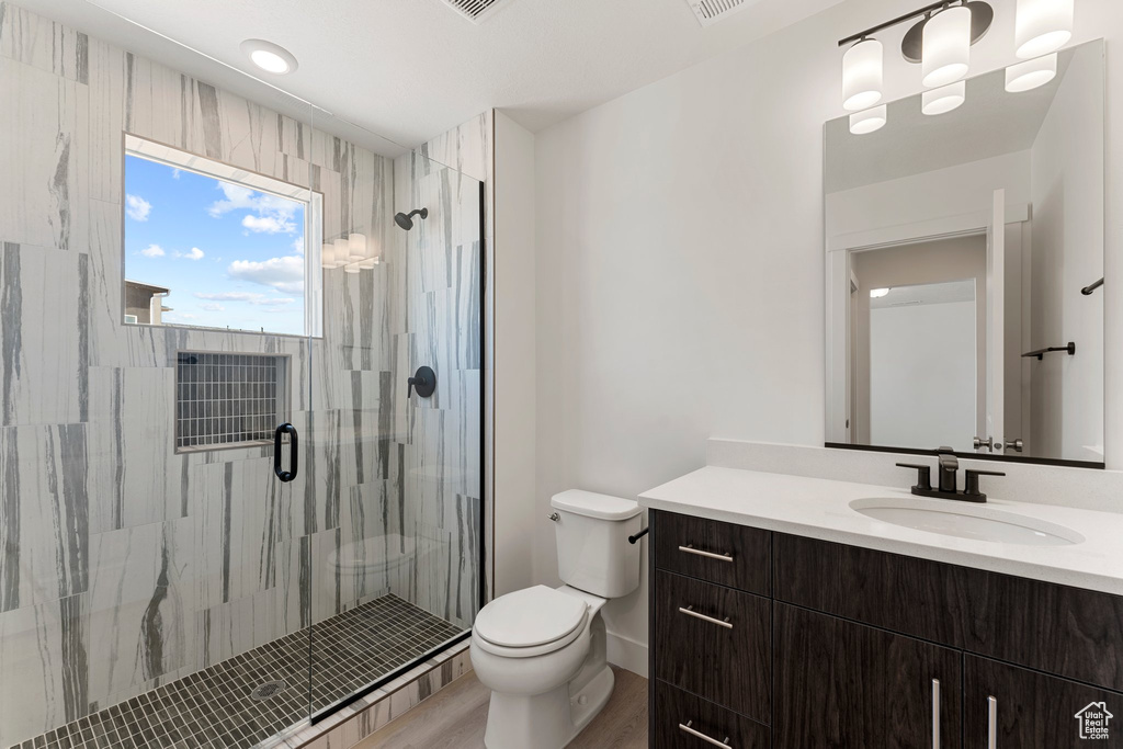 Full bath with vanity, a stall shower, and wood finished floors