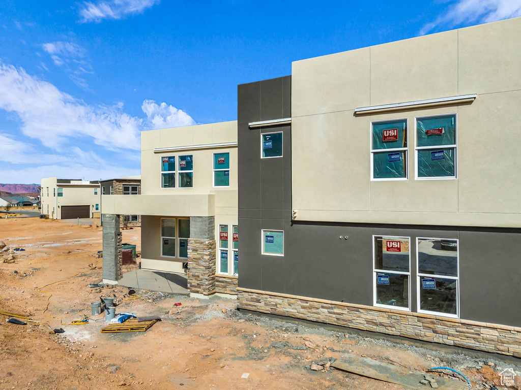 Back of property featuring stucco siding and stone siding