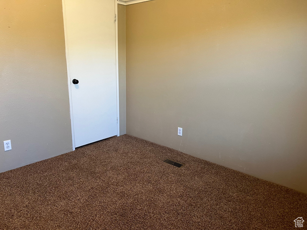 Carpeted spare room featuring visible vents