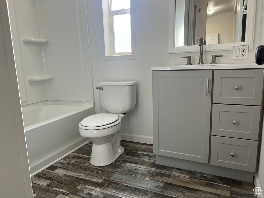 Bathroom with toilet, vanity, wood finished floors, and baseboards
