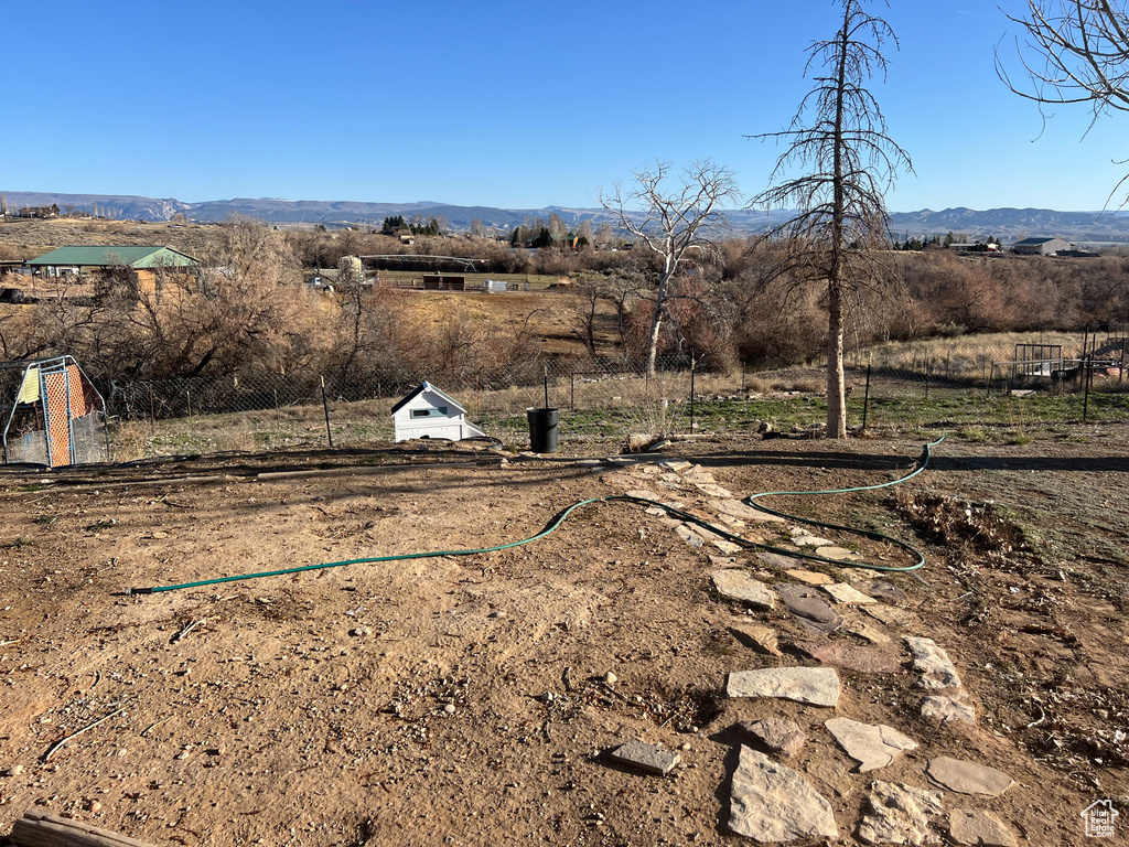 View of yard featuring a rural view, a mountain view, and fence