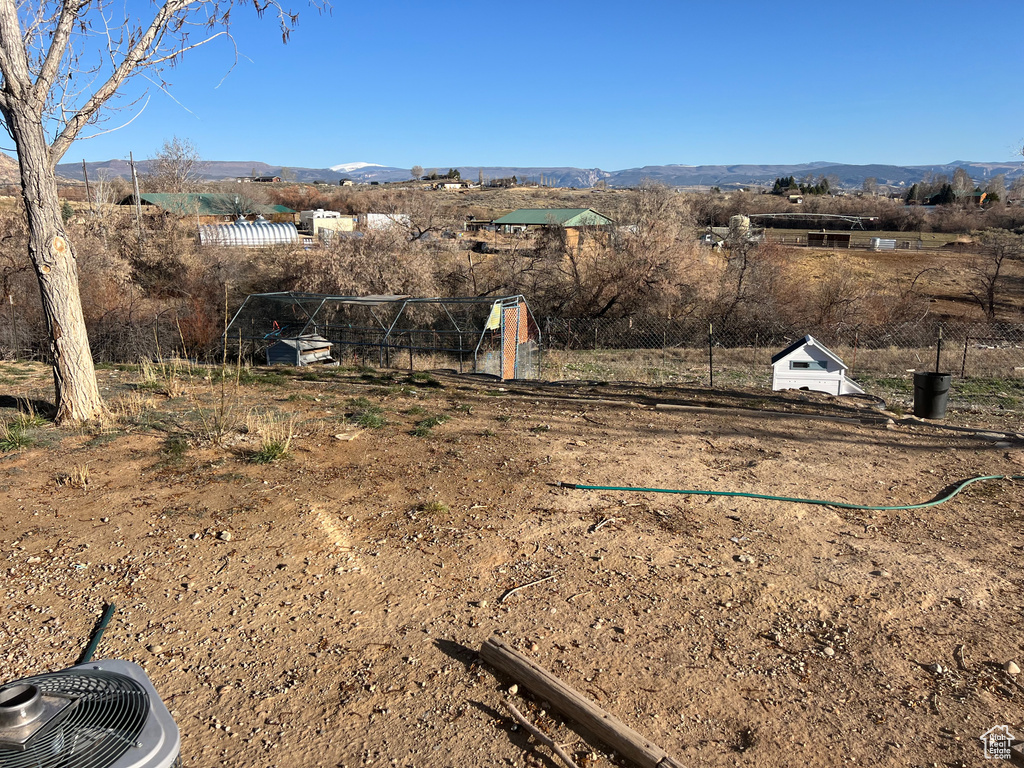 View of yard with a rural view, fence, and a mountain view