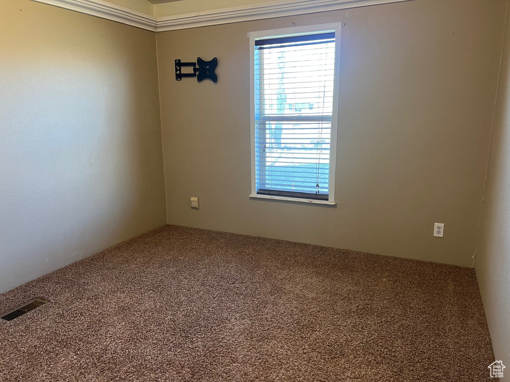 Carpeted empty room featuring visible vents
