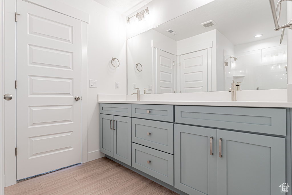 Bathroom featuring double vanity, a shower stall, and wood finished floors
